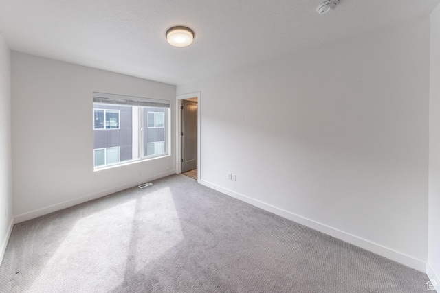 carpeted spare room featuring visible vents and baseboards