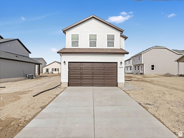 traditional-style home featuring cooling unit, an attached garage, and driveway