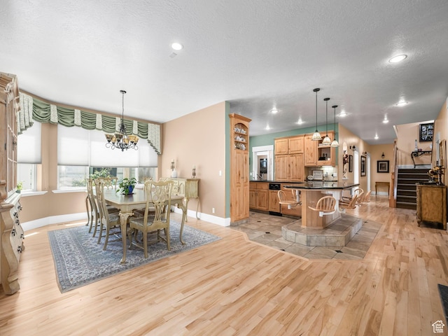 dining area with baseboards, light wood finished floors, a textured ceiling, a chandelier, and stairway
