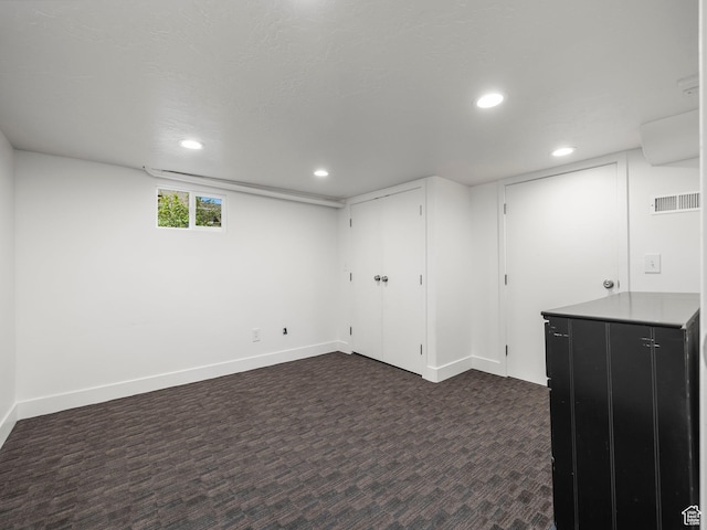 basement featuring dark colored carpet, recessed lighting, and baseboards