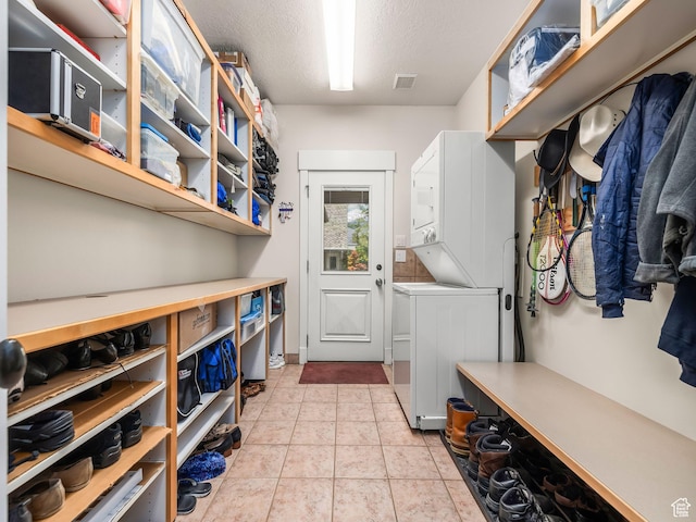 laundry area with stacked washer / dryer and a textured ceiling