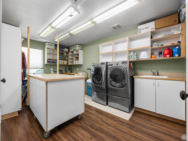 laundry area featuring washer and clothes dryer, dark wood-style flooring, a textured ceiling, and cabinet space