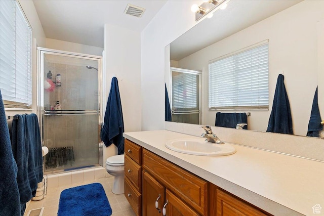 full bathroom featuring toilet, vanity, a stall shower, and visible vents