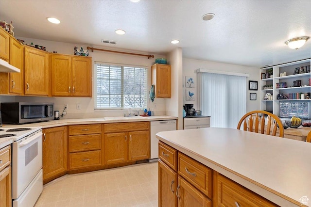 kitchen featuring light countertops, visible vents, a sink, and white appliances