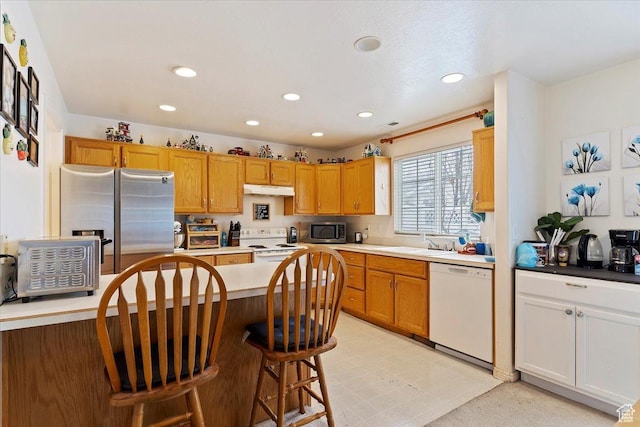 kitchen with a kitchen bar, a sink, appliances with stainless steel finishes, and recessed lighting
