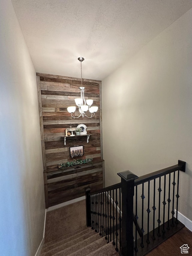 338 S 1230 E, Tooele, UT 84074 - stairway featuring a textured ceiling, an accent wall, wood walls, a notable chandelier, and baseboards