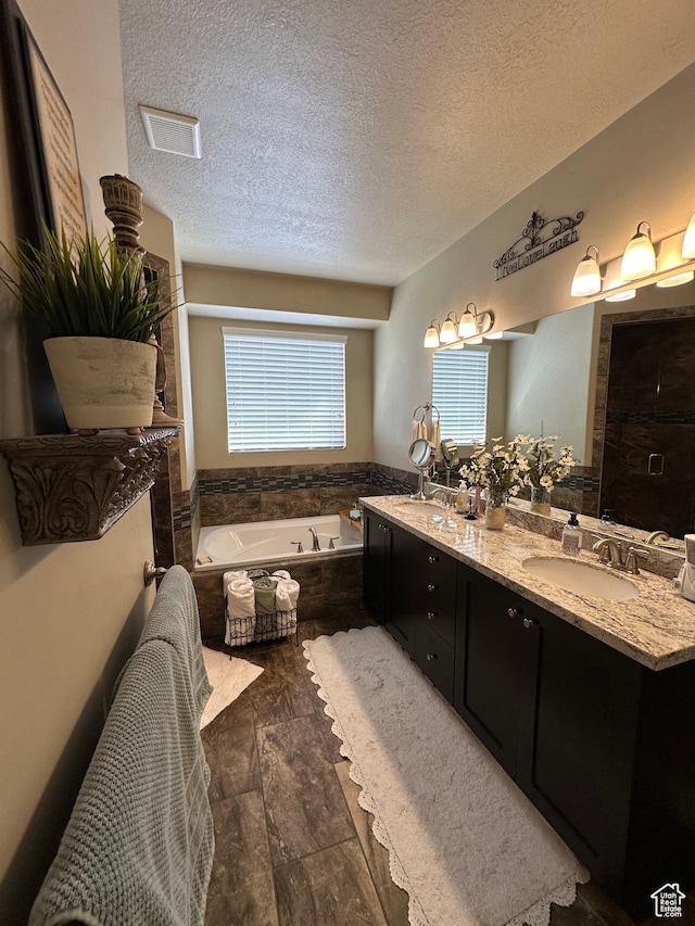 338 S 1230 E, Tooele, UT 84074 - full bath featuring a bath, a textured ceiling, visible vents, a sink, and double vanity
