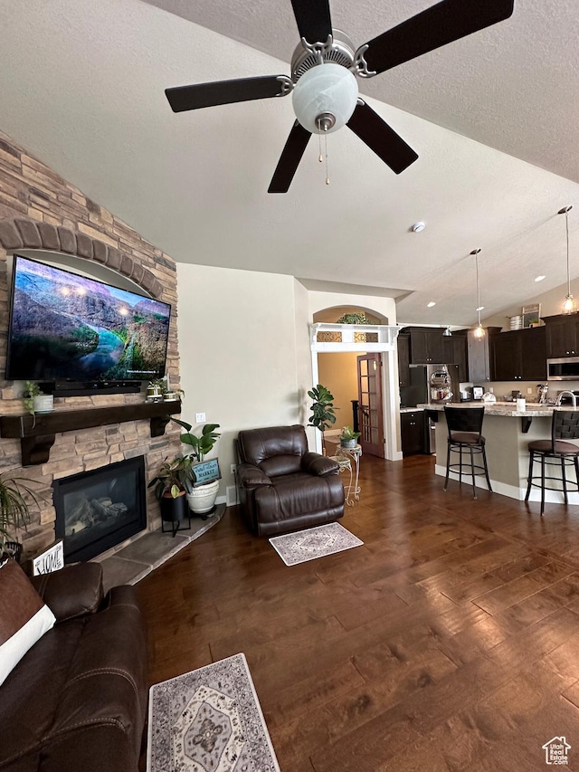 338 S 1230 E, Tooele, UT 84074 - living room featuring ceiling fan, a fireplace, a textured ceiling, vaulted ceiling, and dark wood-style flooring