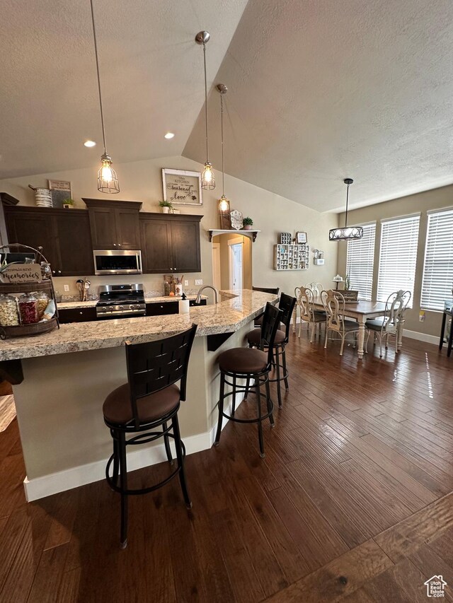 338 S 1230 E, Tooele, UT 84074 - kitchen with stainless steel appliances, a breakfast bar, a textured ceiling, and dark wood finished floors
