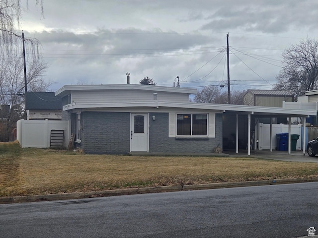 view of front of home with a front lawn, a carport, and fence