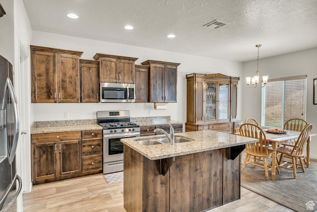 6116 S Rocky Talus Way, St George, UT 84790 - kitchen with light stone counters, stainless steel appliances, a sink, visible vents, and light wood-style floors