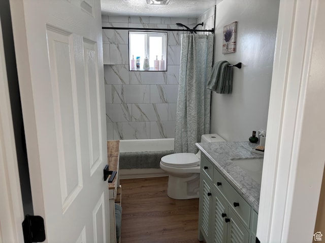 full bathroom featuring a textured ceiling, toilet, shower / tub combo, wood finished floors, and vanity