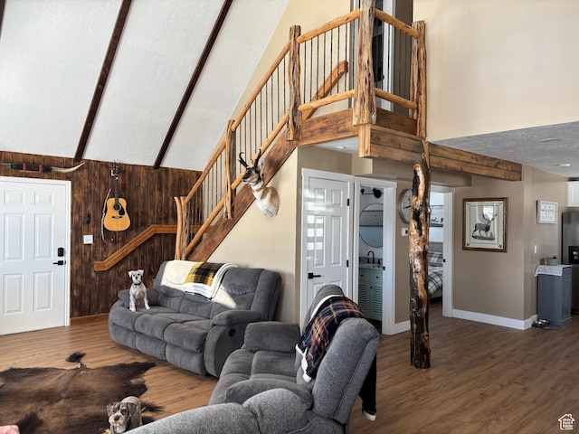 living room with wood walls, stairs, high vaulted ceiling, and wood finished floors