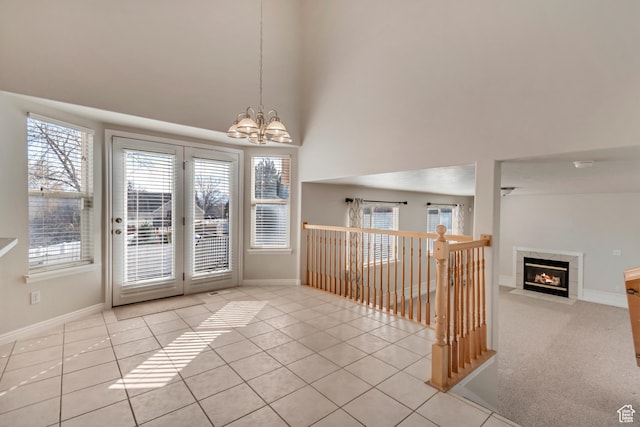 interior space with carpet floors, tile patterned flooring, baseboards, a chandelier, and a tile fireplace