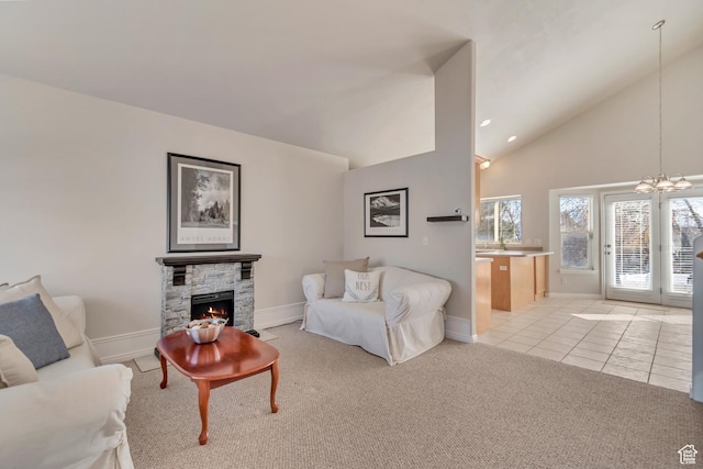 living room featuring a notable chandelier, high vaulted ceiling, a stone fireplace, light tile patterned flooring, and light colored carpet