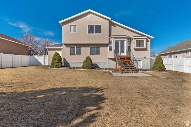 rear view of property featuring a fenced backyard, a lawn, french doors, and stucco siding