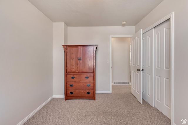 unfurnished bedroom with visible vents, baseboards, light colored carpet, and a closet