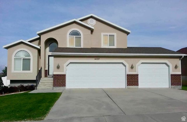 view of front facade featuring brick siding, stucco siding, and concrete driveway