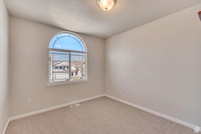 spare room featuring visible vents, carpet flooring, and baseboards