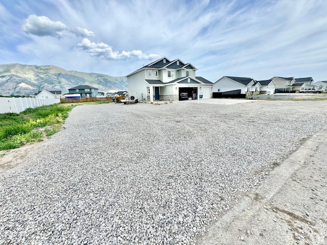 9444 N 4800 W, Elwood, UT 84337 - view of front of home featuring gravel driveway, a mountain view, stone siding, an attached garage, and a residential view