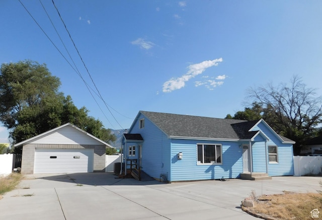 single story home with an outbuilding, a shingled roof, fence, and a garage