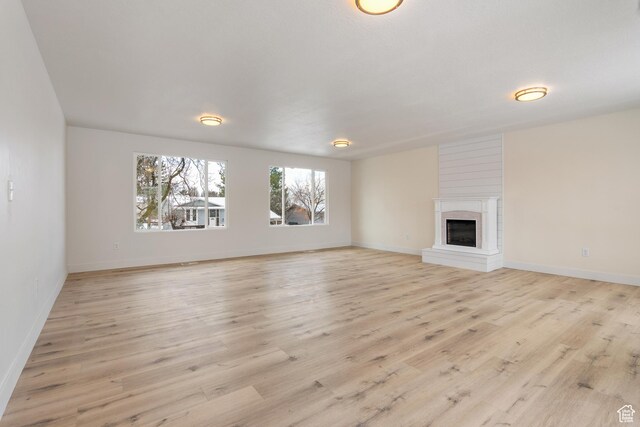 980 W 230 N, Orem, UT 84057 - unfurnished living room with light wood-type flooring, a glass covered fireplace, and baseboards