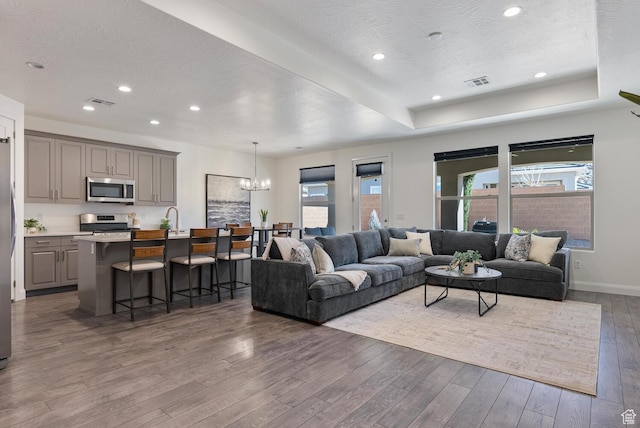 1392 N Marfil Way, Washington, UT 84780 - living room featuring visible vents, a tray ceiling, an inviting chandelier, hardwood / wood-style flooring, and a textured ceiling