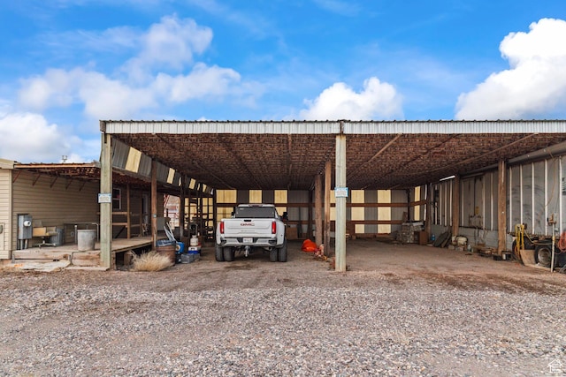 view of parking / parking lot with a detached carport, driveway, and a pole building