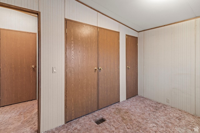 unfurnished bedroom with visible vents, multiple closets, carpet, and ornamental molding