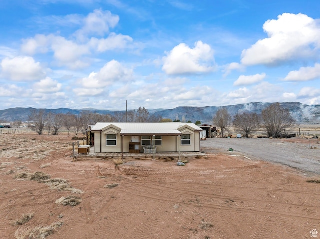 view of front facade featuring a mountain view, driveway, covered porch, and metal roof
