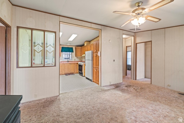 unfurnished living room with a ceiling fan, light colored carpet, visible vents, and a sink