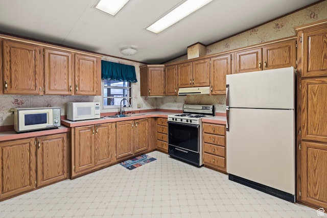kitchen with a sink, range hood, white appliances, light floors, and vaulted ceiling