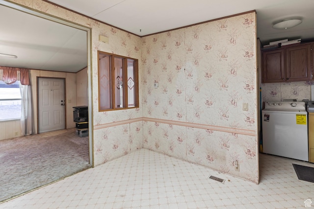 interior space with wallpapered walls, a wood stove, washer / clothes dryer, and light floors