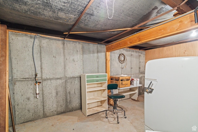 unfinished basement with white fridge
