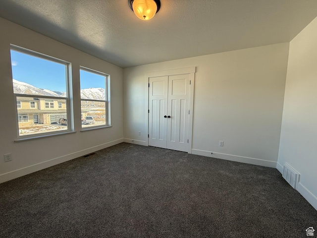 3269 S 1000 W, Nibley, UT 84321 - unfurnished bedroom with dark colored carpet, visible vents, baseboards, and a textured ceiling