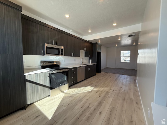 3269 S 1000 W, Nibley, UT 84321 - kitchen featuring light wood-style flooring, a sink, light countertops, dark brown cabinetry, and appliances with stainless steel finishes