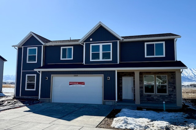 view of front facade with a porch, concrete driveway, a garage, and stone siding