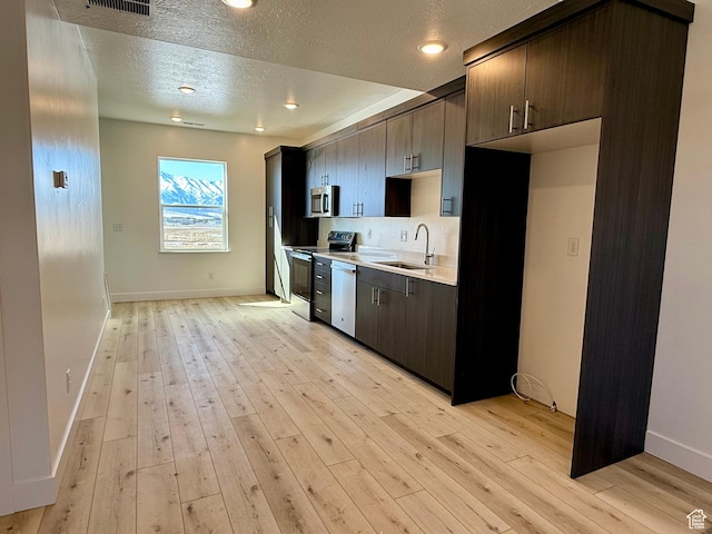 3269 S 1000 W, Nibley, UT 84321 - kitchen featuring a sink, light countertops, dark brown cabinets, appliances with stainless steel finishes, and light wood-type flooring