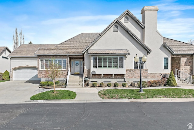 539 E Normandy Dr, Provo, UT 84604 - view of front facade featuring a chimney, a garage, concrete driveway, brick siding, and stucco siding