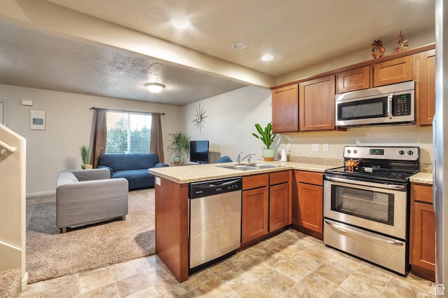 kitchen featuring a peninsula, a sink, stainless steel appliances, light countertops, and open floor plan