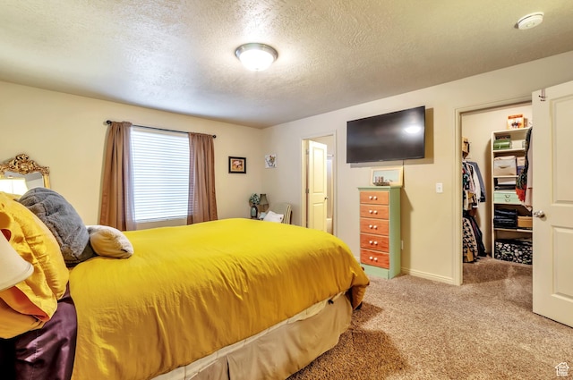 carpeted bedroom with a closet, baseboards, a textured ceiling, and a spacious closet