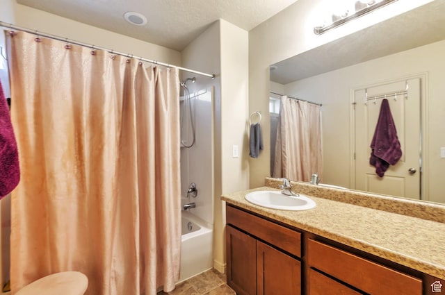 full bathroom featuring a textured ceiling, shower / bath combo, and vanity