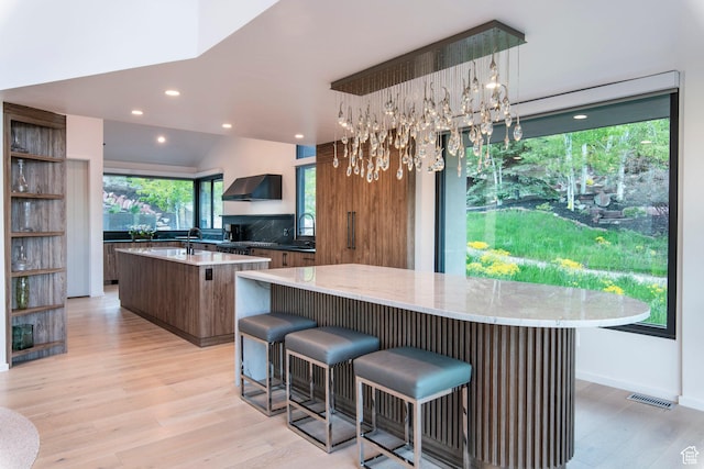 2559 Lupine Ln, Park City, UT 84060 - kitchen featuring a center island, wall chimney exhaust hood, light wood-style floors, recessed lighting, and a kitchen breakfast bar