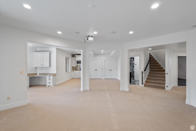 unfurnished living room featuring baseboards, recessed lighting, stairs, and light colored carpet