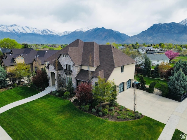 exterior space featuring a residential view, an attached garage, driveway, stone siding, and a mountain view