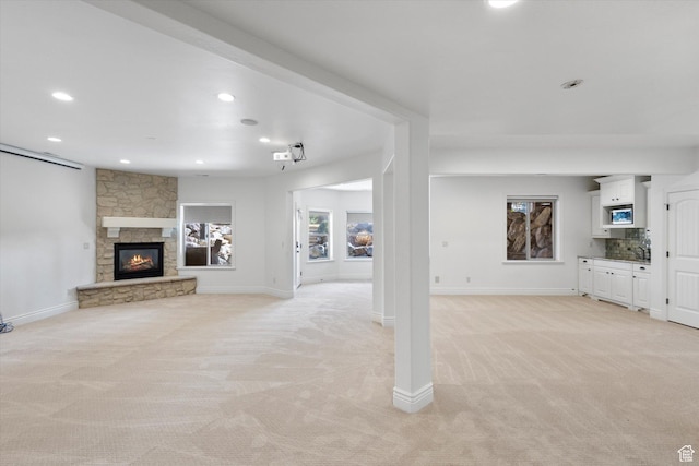 unfurnished living room featuring light colored carpet, a fireplace, baseboards, and recessed lighting