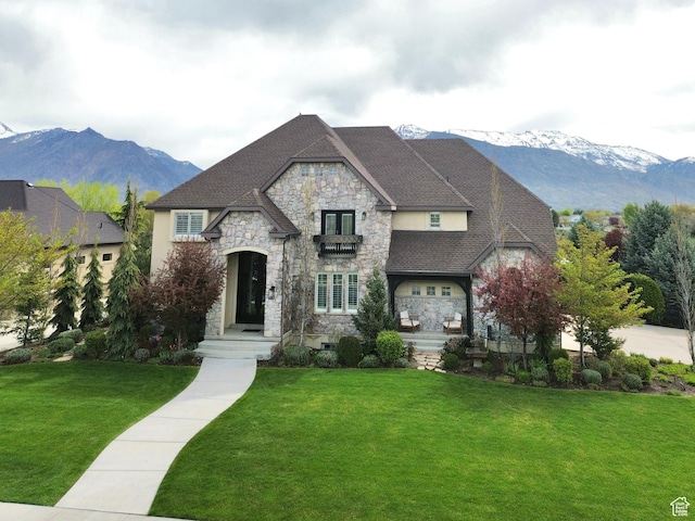 french country inspired facade with a front lawn, a mountain view, and stone siding