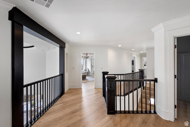 corridor featuring light wood-type flooring, recessed lighting, a notable chandelier, an upstairs landing, and ornamental molding