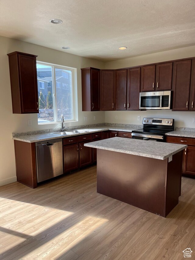 2421 S Blue Water Ln E, Saratoga Springs, UT 84045 - kitchen with light wood-style flooring, a kitchen island, appliances with stainless steel finishes, a sink, and light countertops