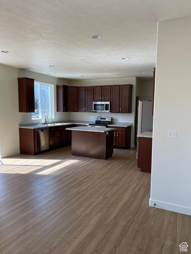 2421 S Blue Water Ln E, Saratoga Springs, UT 84045 - kitchen featuring baseboards, light wood-type flooring, a center island, light countertops, and stainless steel appliances